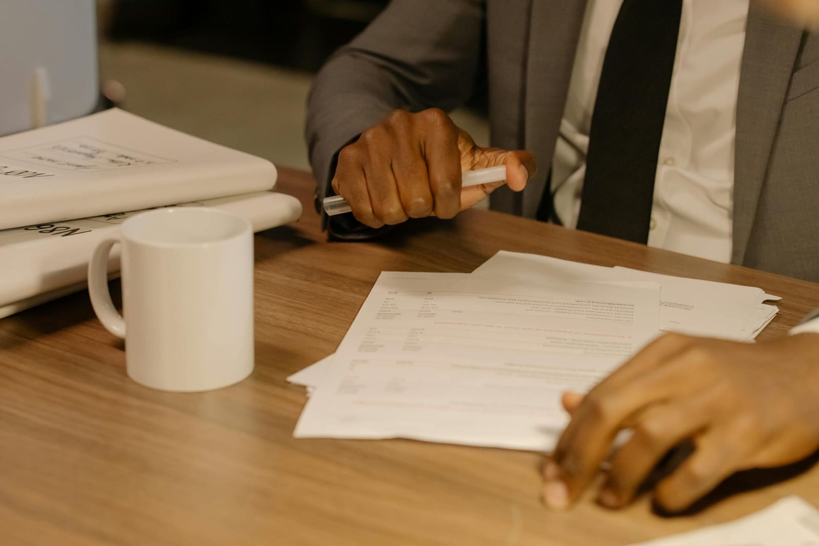 Close-up of a businessman reviewing paperwork on a wooden desk
