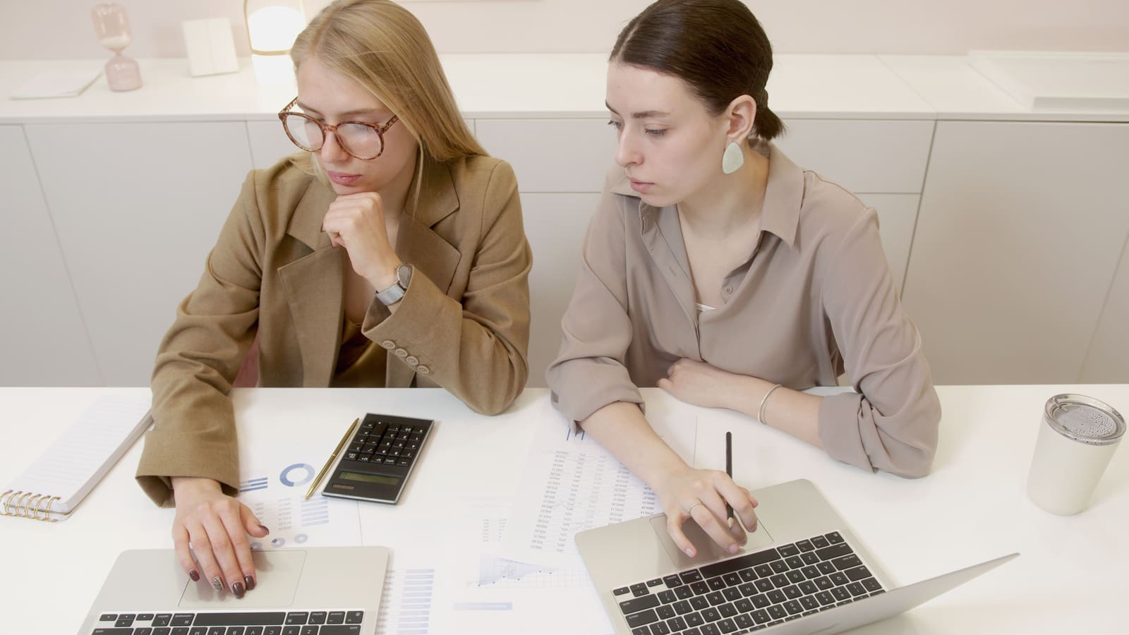 Two colleagues working together at laptops in a modern office